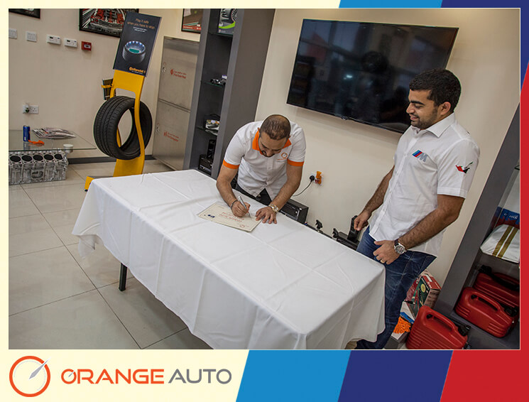 A UAE man signing a certificate at Orange Auto center