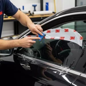 Technician installing genuine 3M ceramic window tint on a luxury SUV inside Orange Auto workshop in Dubai.
